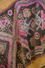 Distressed Oushak rug showing textured pile with vibrant pink, charcoal, and gold hues.