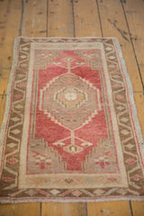 Distressed vintage Oushak rug with faded cherry red, bronze, and beige geometric patterns.