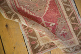 Hand-knotted pile texture of distressed Oushak rug with cherry red, bronze, and sand hues.