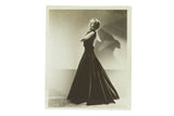 Vintage black and white studio photograph of Carole Lombard in an elegant full-length backless gown.