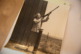 Carole Lombard aiming shotgun, detail of photograph's upper right corner with punched hole.