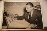 Candid black and white photograph of costume designer Walter Plunkett sketching a dress.