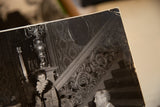 Close-up of the vintage photograph's creased top right corner with visible cracks and wear.