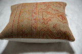 Textured beige side of vintage Turkish rug fragment pillow, faded orange motifs.