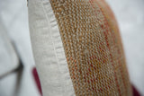 Textured vintage rug fragment pillow edge with a neutral smooth fabric backing.