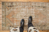 Distressed Oushak rug in beige, terra cotta, and olive, showing mostly even wear.