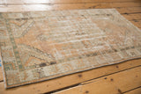 Distressed vintage Oushak rug with visible low pile, in faded beige, sand, terra cotta, and olive.