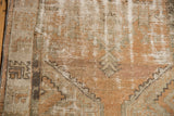 Decorative distressed Oushak rug showing worn pile with olive green, pale terra cotta, and sand.