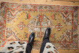 Distressed vintage Oushak runner with golden, madder red, and blue patterns showing worn pile.