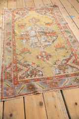 Distressed Oushak rug with geometric palmettes and vines in faded gold, red, and oxidized silver.