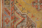 Textural detail of distressed Oushak rug: geometric border and dusty gold field with varied pile.