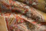 Folded distressed Oushak rug pile with geometric motifs in rust, saffron, and sky blue.