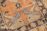 Distressed Oushak rug with visible wear, featuring tangerine, green, and mauve serrated patterns.