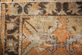 Distressed Oushak rug pile showing wear to knot heads, faded tangerine and charcoal.