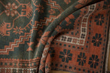 Distressed Oushak rug, worn pile and geometric floral motifs in faded dusty teal and terra cotta.