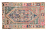 Distressed Oushak rug with faded pink, blue, green geometric medallion and serpent spandrels.