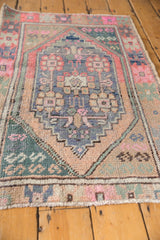 Distressed vintage Turkish Oushak rug's low pile and secured end, in soft pink, beige, and teal.