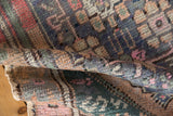 Distressed Oushak rug's worn pile texture with dusty teal, pink, and beige patterns.