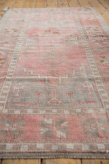 Distressed texture, geometric border, and faded patterns of the dusty blush Oushak rug.