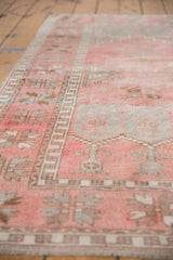 Distressed Oushak rug detail, dusty pink with time-softened plant motifs and geometric border.