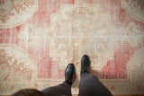 Distressed vintage Oushak rug with soft, worn texture and faded raspberry red, ivory hues.