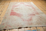 Distressed vintage Oushak rug detail, faded red and ivory wool pile, mostly even wear.