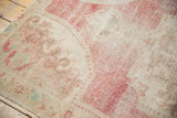 Distressed vintage Oushak rug pile texture with worn red and ivory motifs.