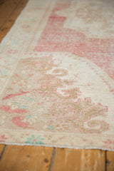 Distressed vintage Oushak rug's low pile, revealing muted ivory, raspberry, and turquoise.
