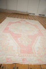 Distressed Oushak rug close-up, highlighting rose, blush, ivory abrashed field with pearl motifs.