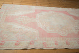 Faded rose and ivory pearl design detail on a distressed vintage Oushak rug border.