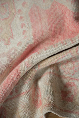 Textured distressed pile of a vintage Oushak rug in soft rose, blush, and ivory.