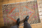 Distressed vintage Oushak rug with pale blue, terra cotta, and pink tones underfoot.