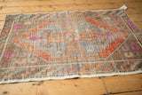 Distressed Oushak rug's worn texture, side selvage, checker border in terra cotta and blue.