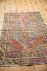 Distressed Oushak rug's worn checker ribbon border with terra cotta, pink, and mint green.