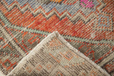Folded corner of a distressed Oushak rug, showing geometric pattern and its reverse.