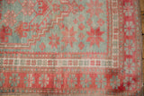 Corner of distressed Oushak rug showing pale raspberry starburst and silver slate motifs.