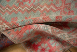 Close-up of distressed vintage Oushak rug pile, showing silver slate and pale raspberry patterns.