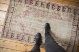 Worn texture of a distressed Oushak rug with faded ivory and plum tones underfoot.