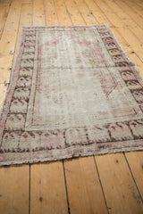 Distressed vintage Oushak rug showing visible foundation, faded plum, and ivory patterns.