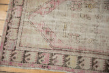 Distressed vintage Turkish Oushak rug corner, showing plum, ivory patterns, foundation wear.