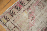 Distressed Oushak rug texture detail, with worn ivory foundation and pale plum patterns.