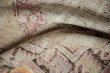 Distressed vintage Oushak rug showing worn pile, visible foundation, and plum, ivory, charcoal hues.