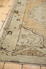 Distressed vintage Oushak rug corner, dusty gold and brown curvilinear border patterns.