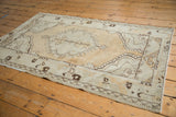 Distressed texture of the Oushak rug's bottom right corner, showing chocolate brown patterns and intact side cord.