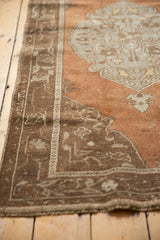 Distressed Oushak rug border: chocolate brown meandering vines on a worn abrashed field.