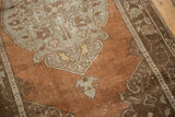 Distressed vintage Oushak rug's chestnut brown field with silver germinating floral motifs.