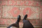 Decorative distressed Oushak rug with faded dusty blush, ivory, and chocolate geometric patterns.