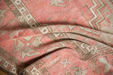Distressed Oushak rug texture with dusty blush, ivory, and chocolate geometric patterns.