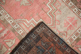 Distressed Oushak rug corner showing worn dusty blush pile and dark chocolate reverse.