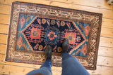 Hand-knotted vintage Hamadan rug displaying navy field, triple medallion, and feet for scale.